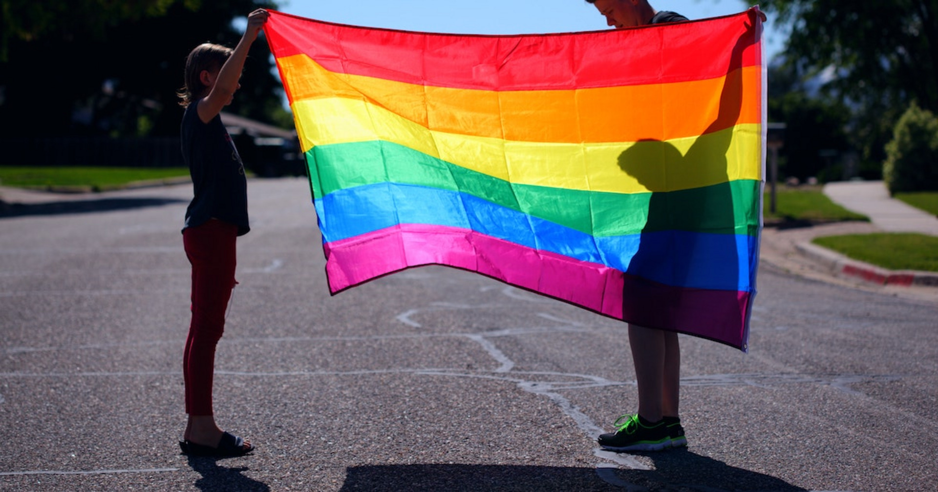 Zwei Personen halten eine Prideflagge hoch.