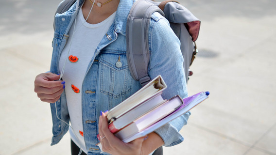 Eine junge Frau hält Bücher in den Händen.