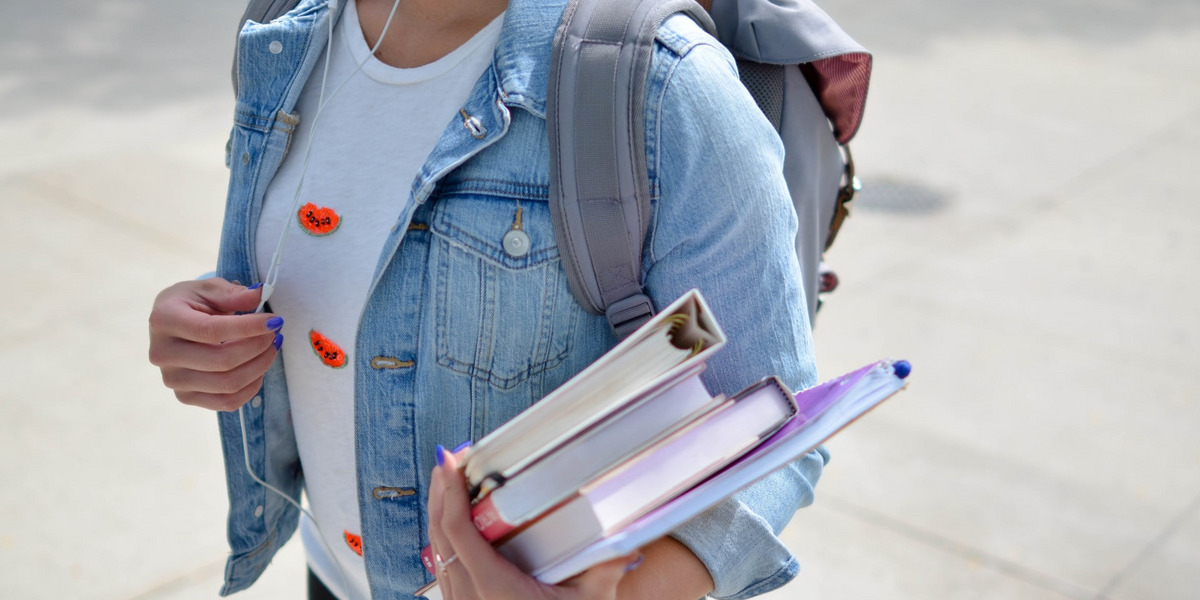 Eine junge Frau hält Bücher in den Händen.