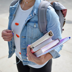 Eine junge Frau hält Bücher in den Händen.