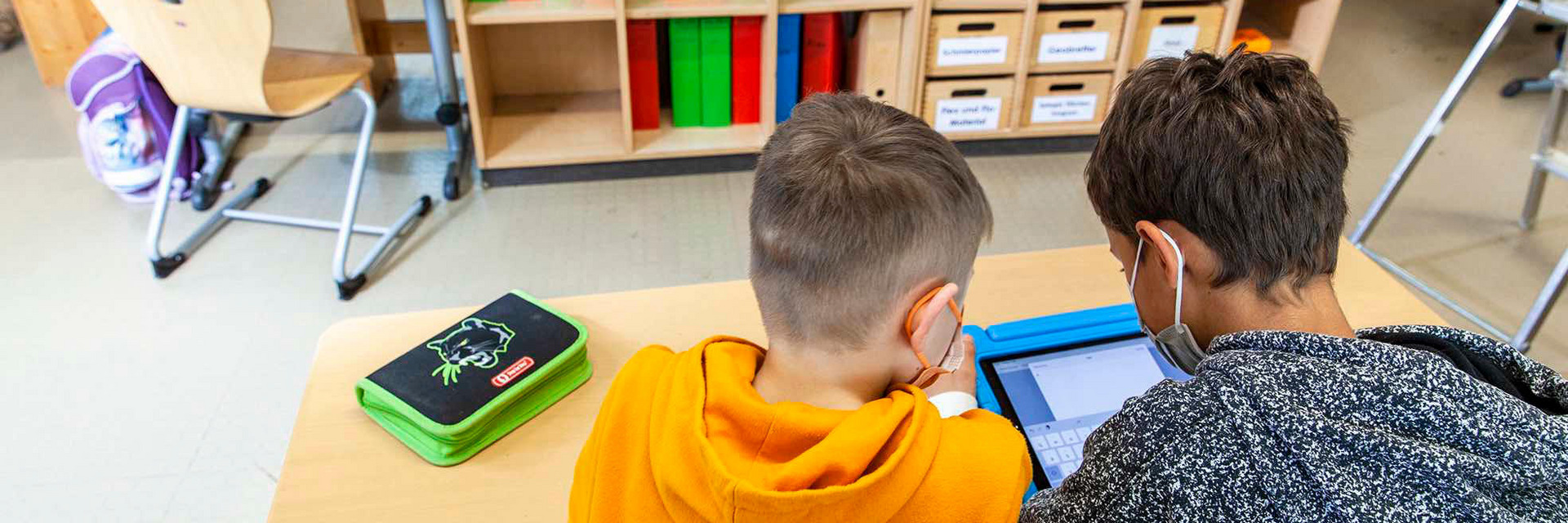 Zwei Schulkinder lernen mit einem Tablet in der Schule.