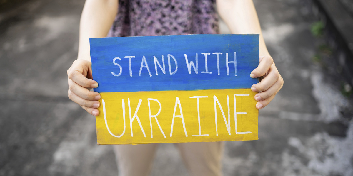 Eine Person hält ein Schild auf dem "Stand With Ukraine" steht