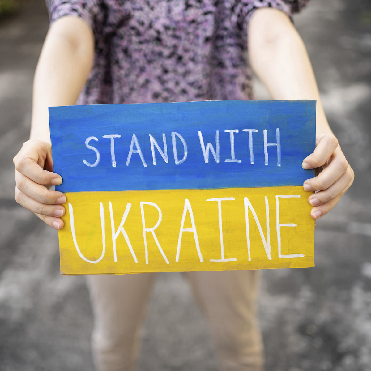 Eine Person hält ein Schild auf dem "Stand With Ukraine" steht