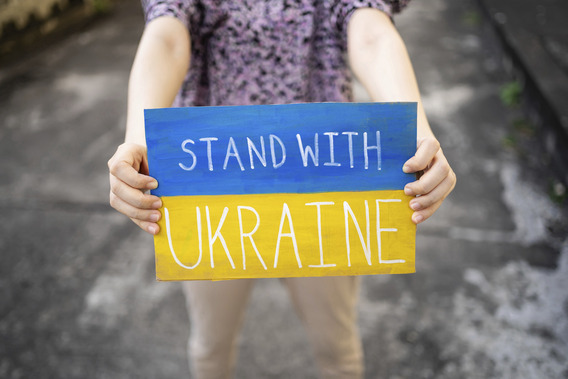 Eine Person hält ein Schild auf dem "Stand With Ukraine" steht