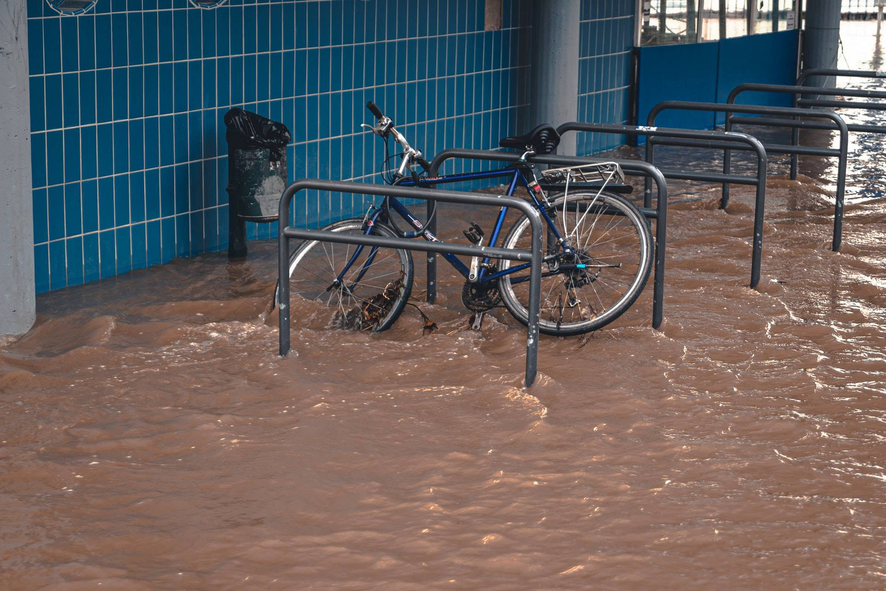 Ein Fahrrad liegt angeschrägt an einem überschwemmten Fahrradständer.
