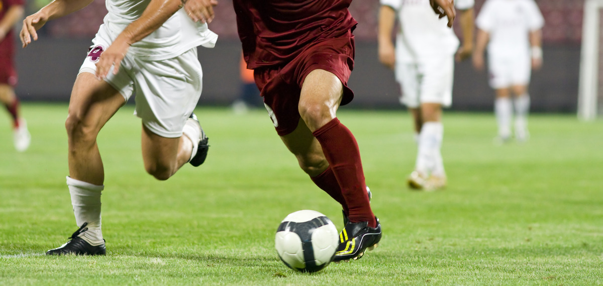AdobeStock_16658833_KONZERN_ST-CC.jpeg Zwei Fußballspieler kämpfen um den Ball