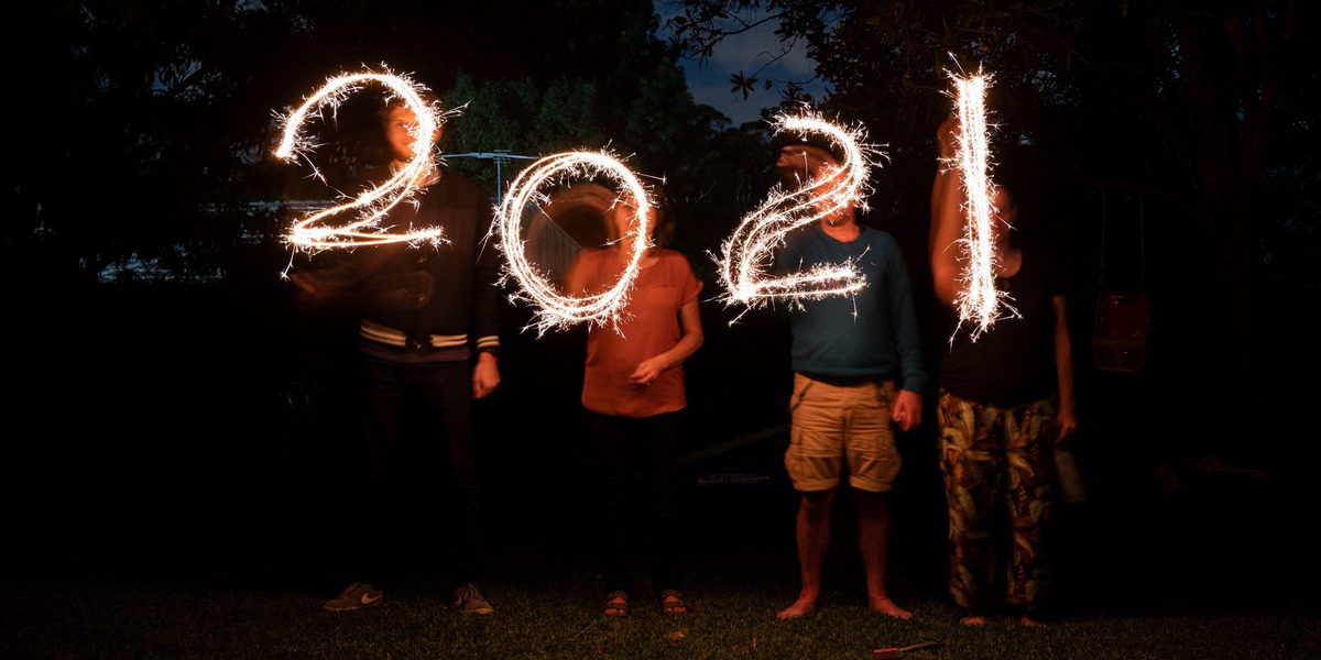 Vier Menschen zeichnen mit Wunderkerzen "2021" in die Nacht.