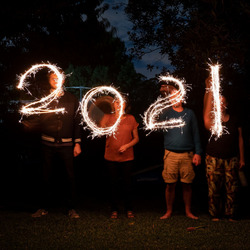 Vier Menschen zeichnen mit Wunderkerzen "2021" in die Nacht.