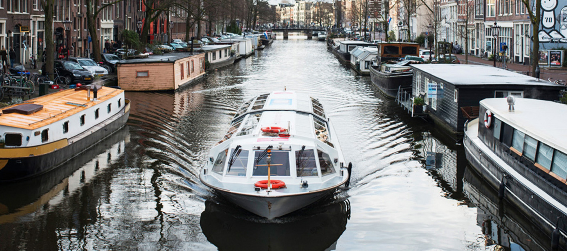 Ein Ausflugsboot fährt durch eine Gracht in Amsterdam