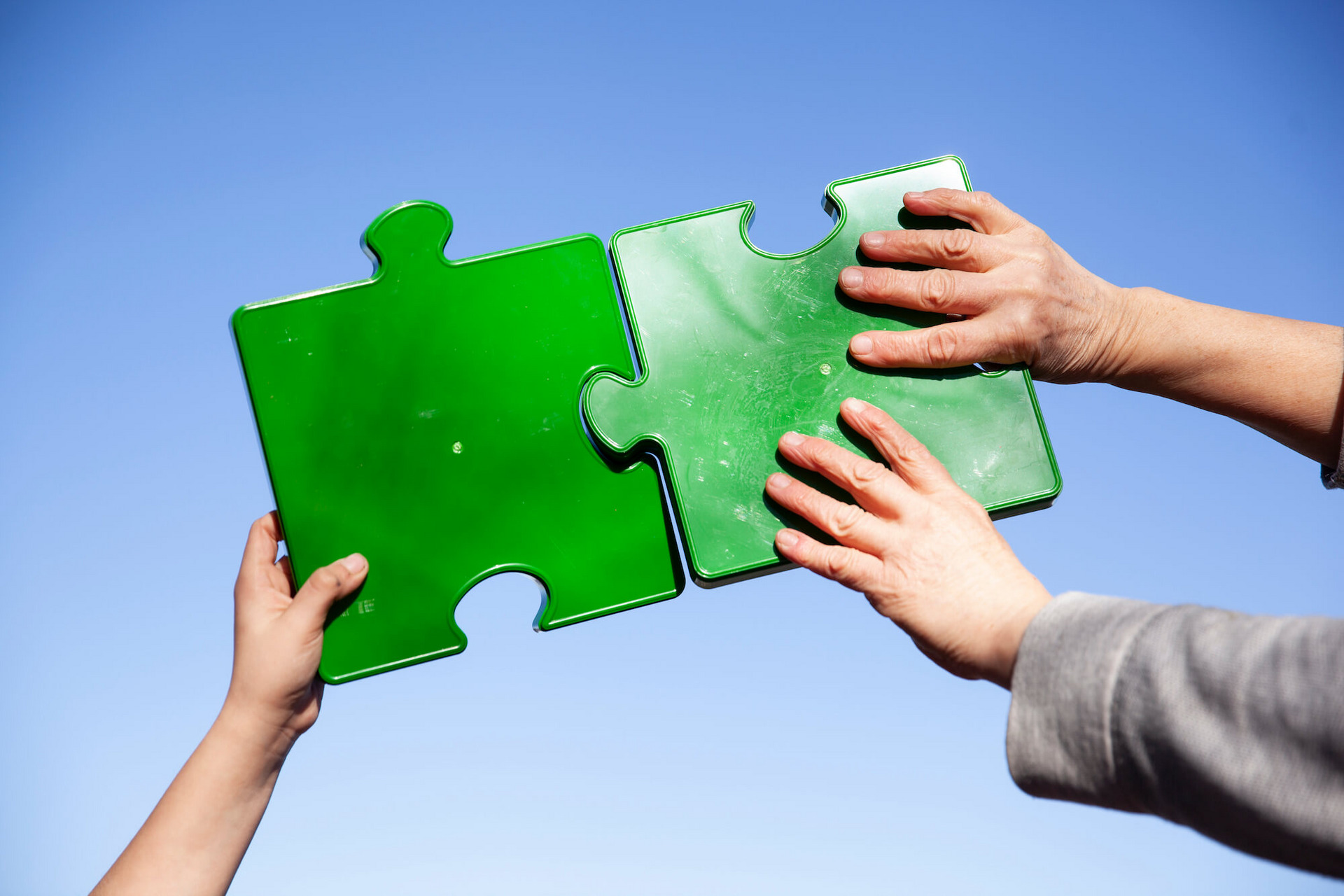 Zwei Personen fügen große grüne Puzzleteile zusammen