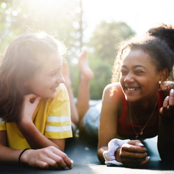 Zwei Teenager liegen auf einem Trampolin und lächeln vor Freude