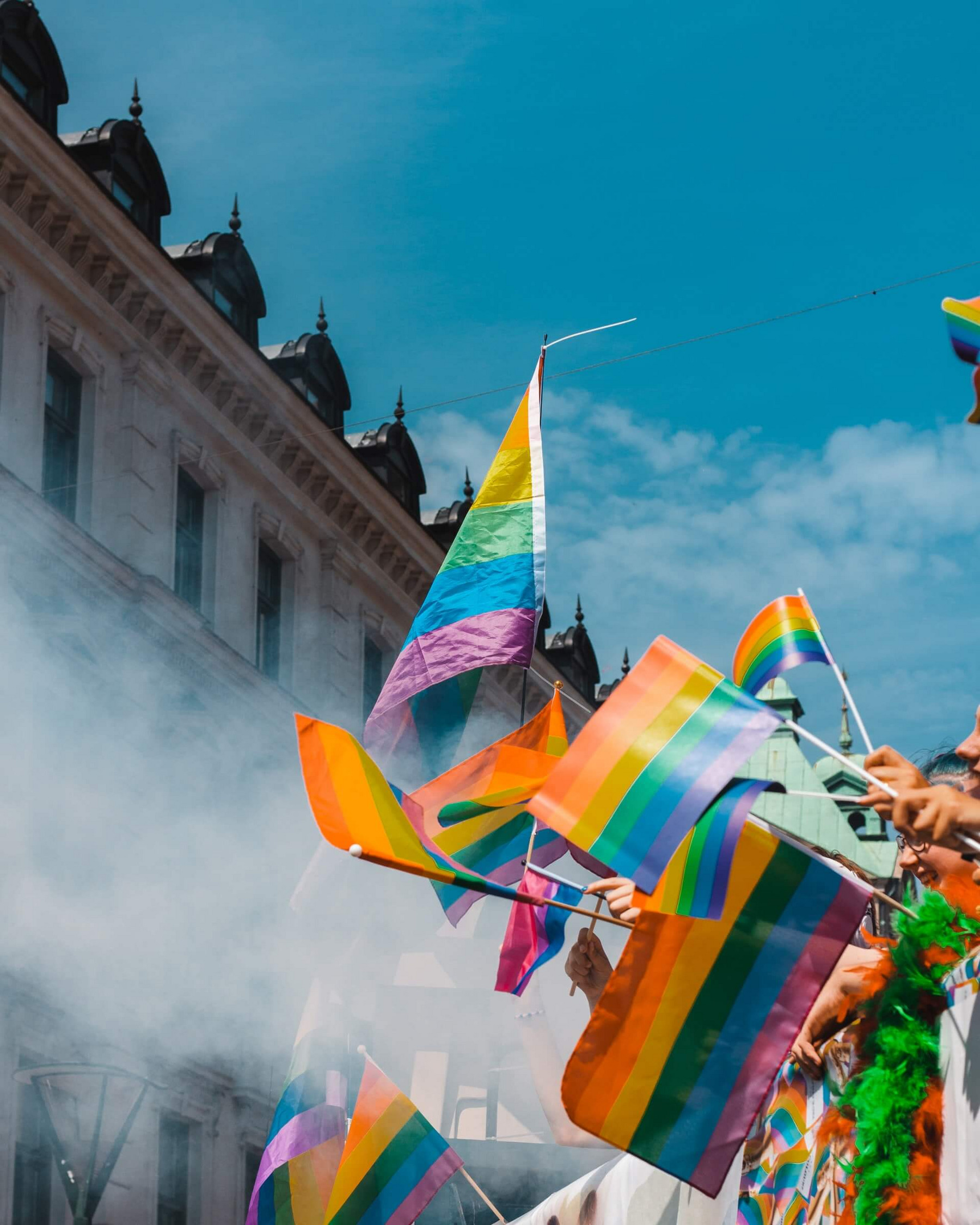 Regenbogenfahnen wehen auf einer Pride-Parade.