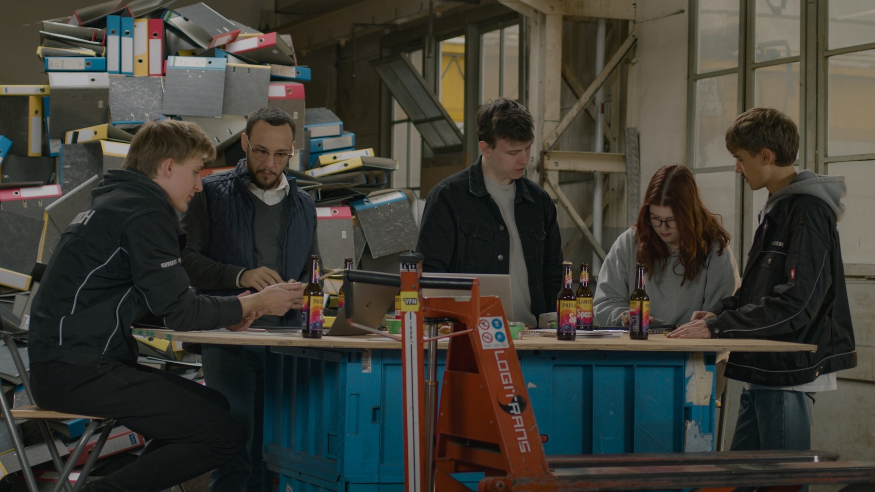 Das Foto zeigt einen Büroraum mit fünf Personen, die an einem Arbeitstisch sitzen.
