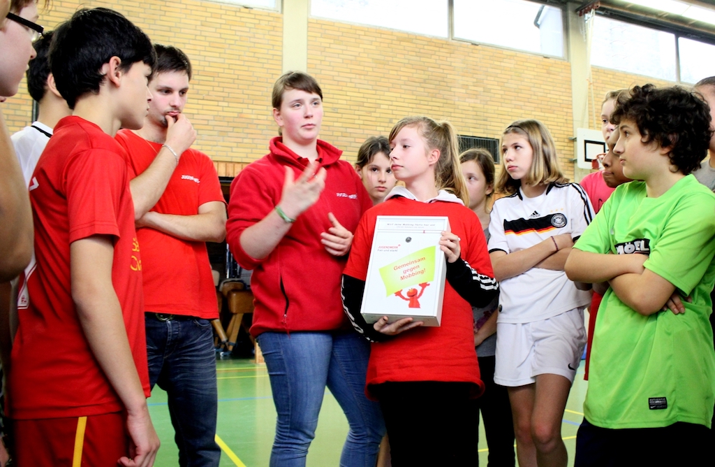 Schüler in einer Turnhalle mit einem Kummerkasten gegen Mobbing