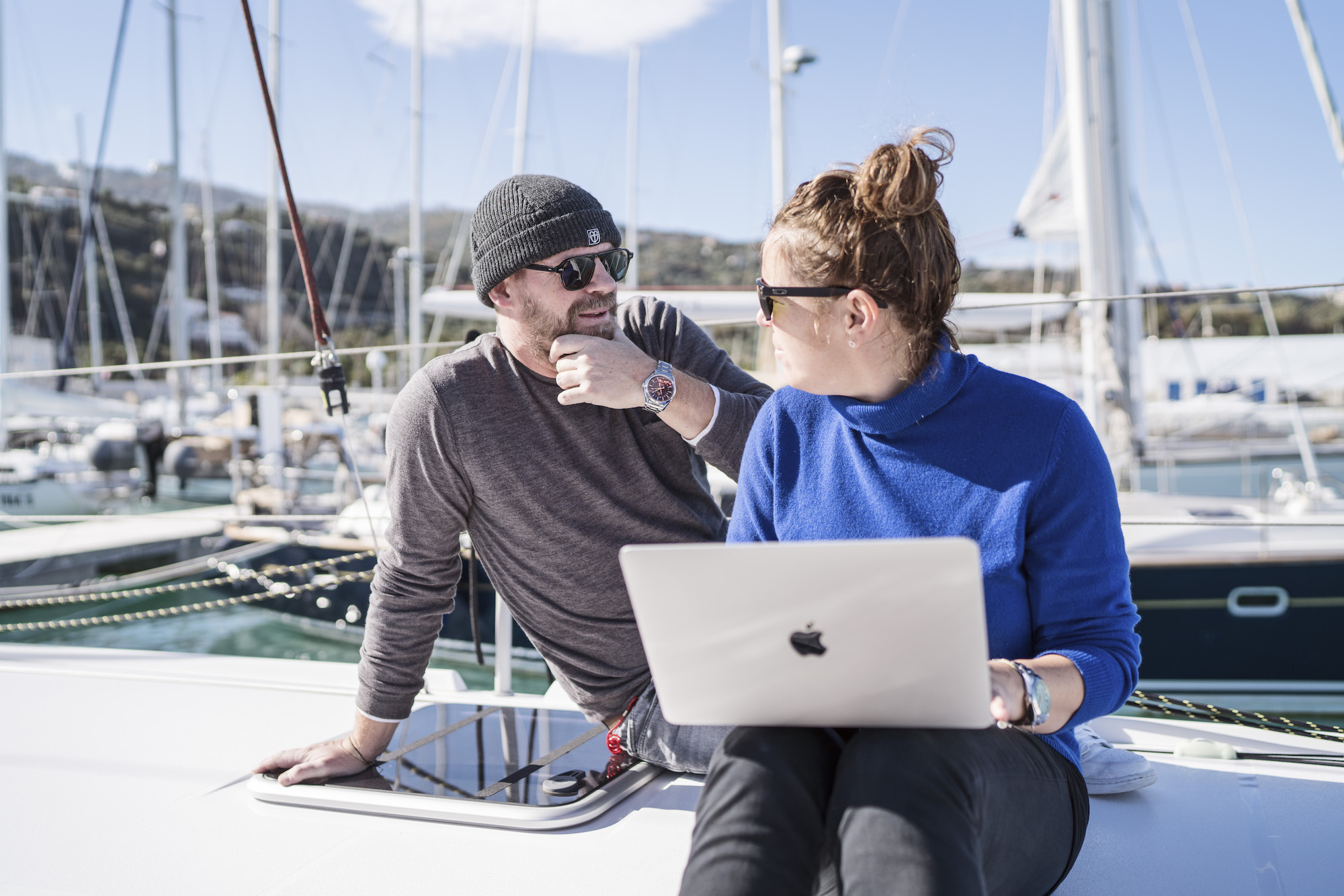 Maren und Matthias Wagener sitzen an Bord ihres Katamarans und arbeiten am Laptop