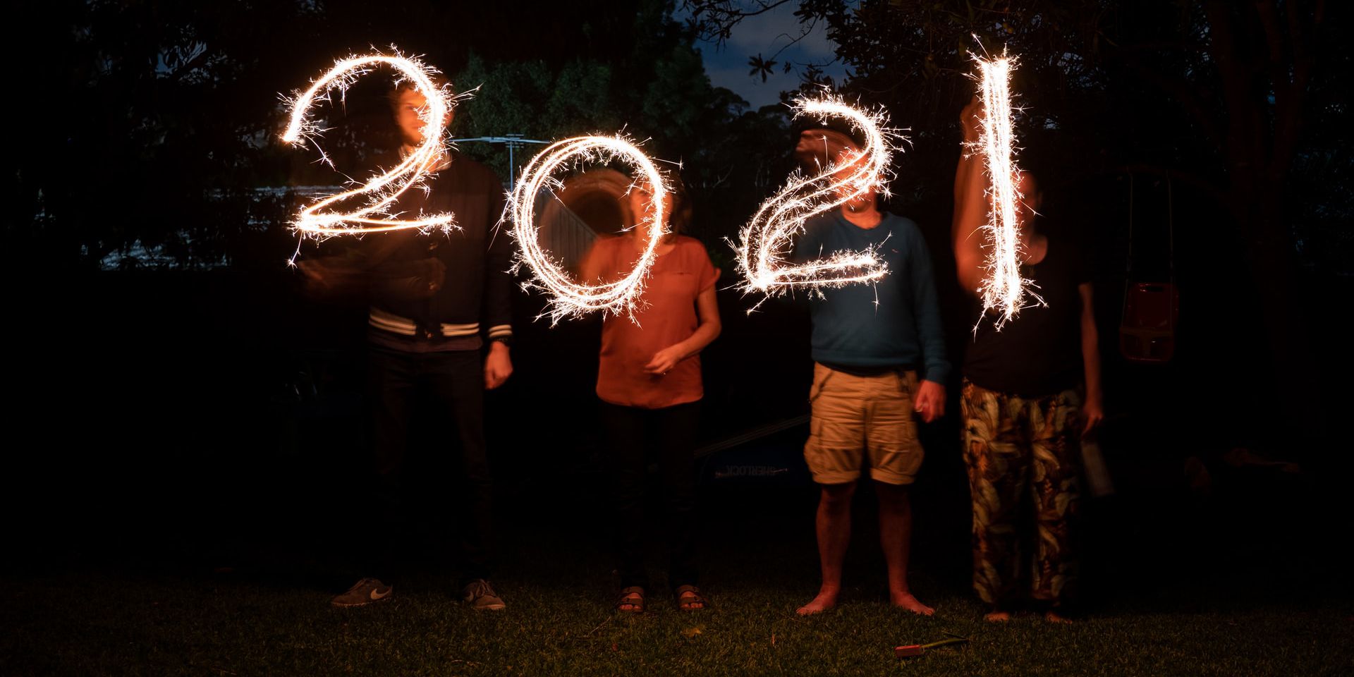 Vier Menschen zeichnen mit Wunderkerzen "2021" in die Nacht.